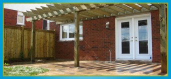 wooden fence and arbor surrounding interlocking stone patio at back of house